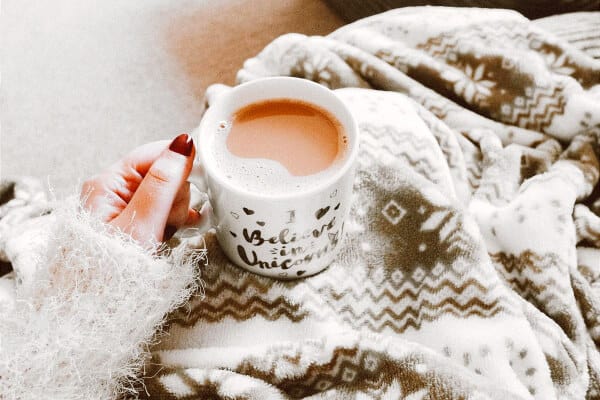 persona con taza y manta por culpa de un resfriado